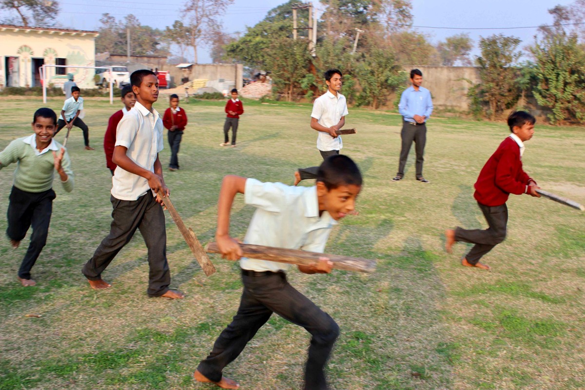 Students playing a game of village style hockey.